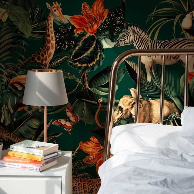 Bedroom with jungle-themed wallpaper featuring animals and plants, lamp, books, and nightstand.