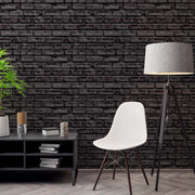 Modern interior with a black brick wallpaper, white chair, and decorative items.