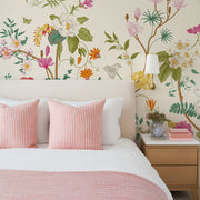Bedroom with chinoiserie wallpaper, pink and white striped pillows, and a wooden nightstand.