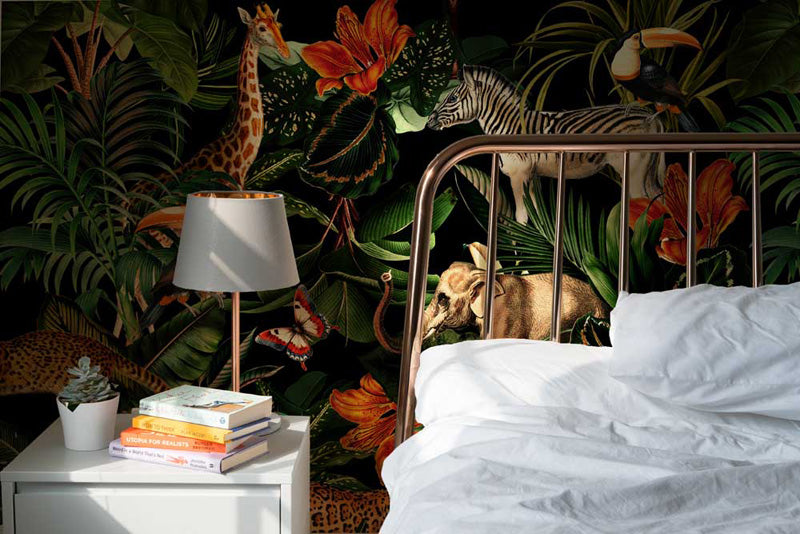 Bedroom with jungle wallpaper, bed, lamp, and books.