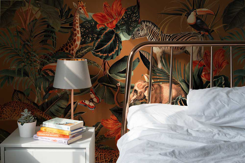 Bedroom with jungle wallpaper, bed, and nightstand with books and lamp.