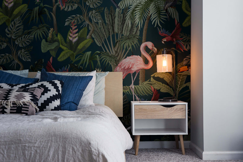 Bedroom with tropical flamingo wallpaper, bed with pillows, and nightstand.