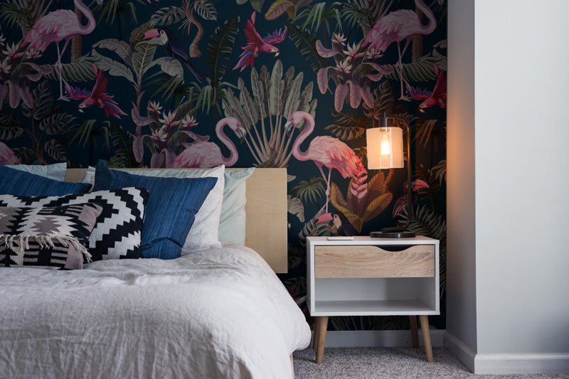 Bedroom with tropical wallpaper, bed, and nightstand.