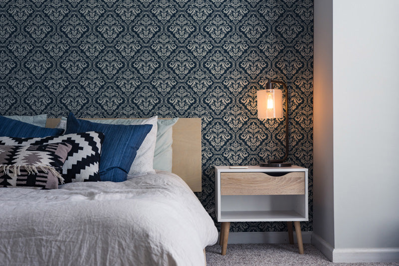 Bedroom with blue wallpaper, bed with pillows, and nightstand.