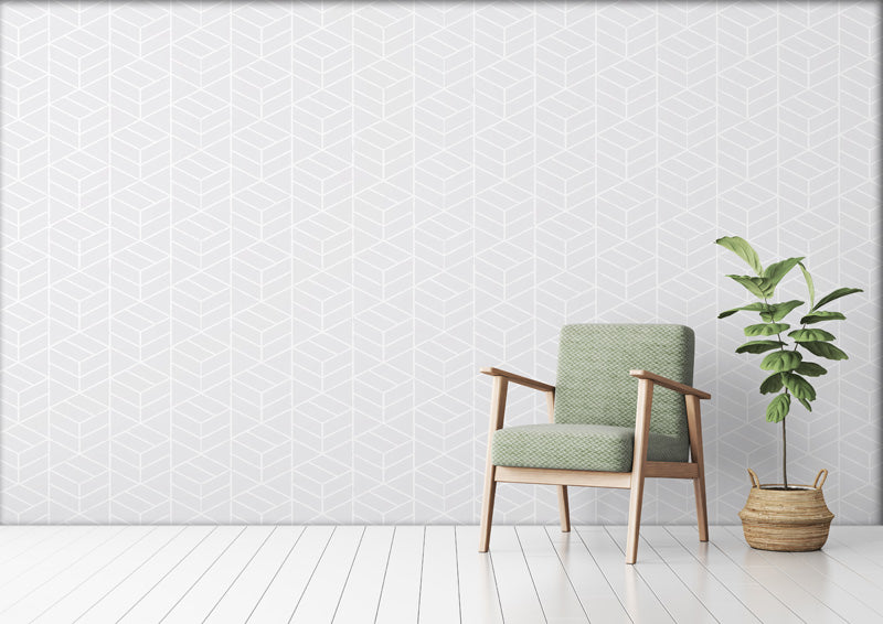 Green armchair with wooden frame against a white wallpaper with a plant on the right.