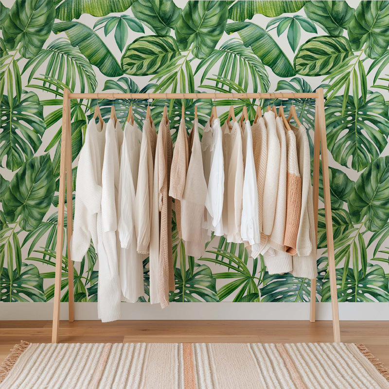 Clothing rack with shirts against a tropical leaf wallpaper