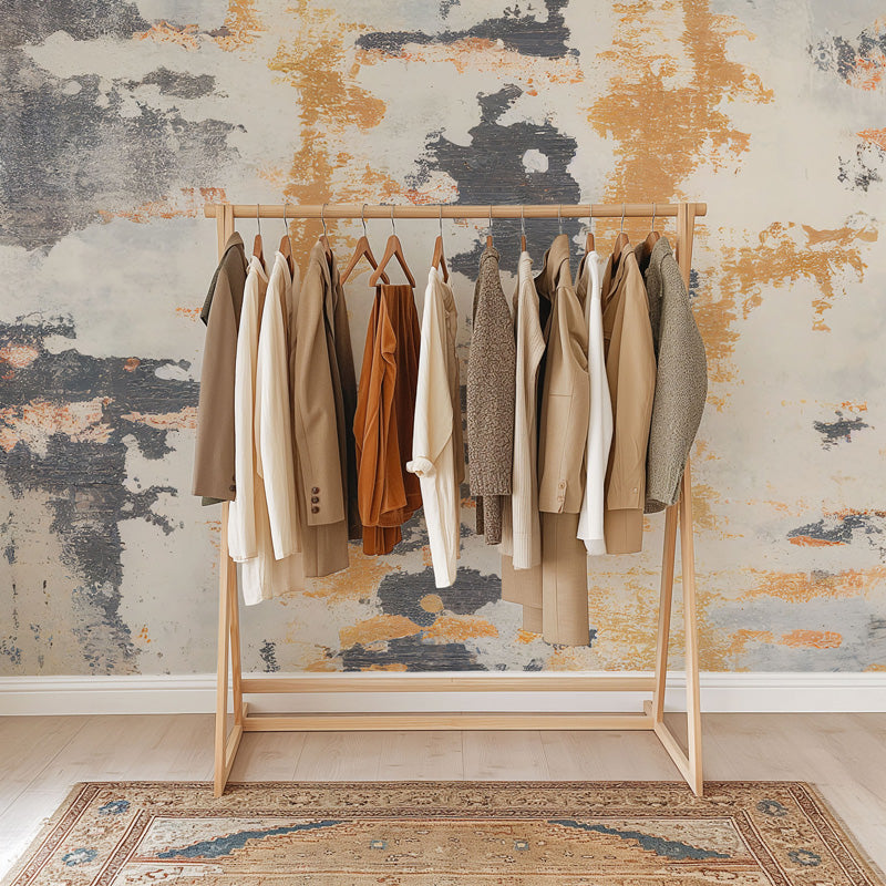 Wooden clothing rack with coats against a textured wallpaper.