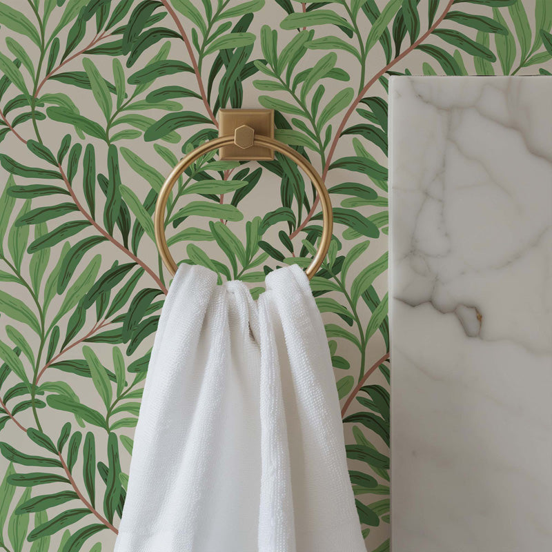 Gold towel ring with a white towel against a green leafy wallpaper background