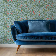 Blue velvet sofa against a floral wallpaper.