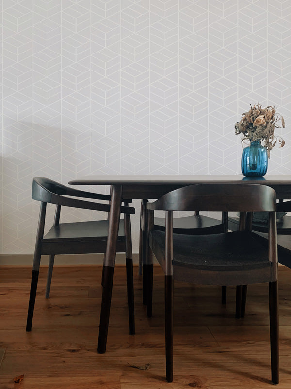 Dining table with chairs against a white wallpaper.