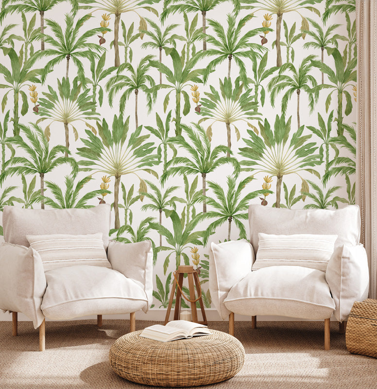 Living room with white armchairs and a woven ottoman against a palm tree wallpaper.