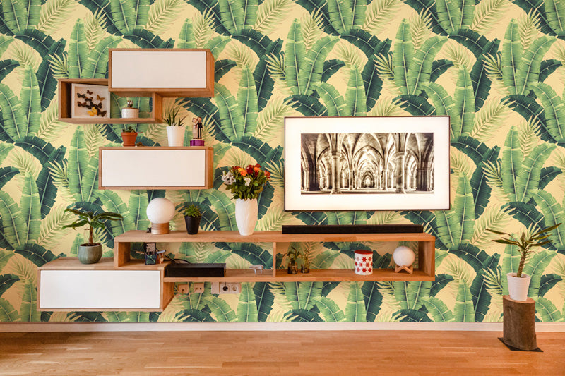 Room interior with wooden shelves against a tropical leaf wallpaper.