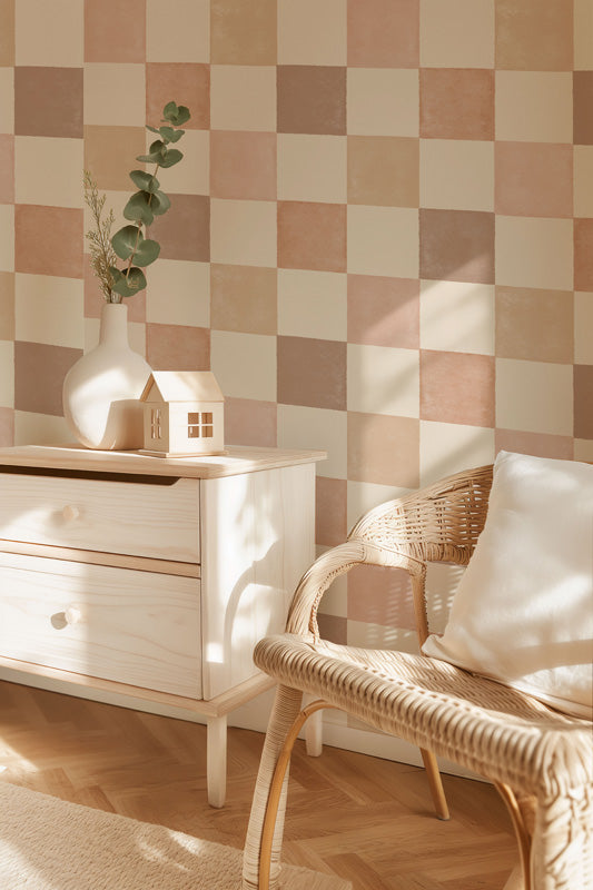 Nursery room with checkered wallpaper, white dresser, and wicker chair.