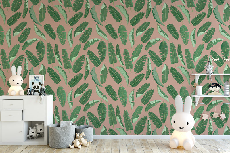 Children's room with pink wallpaper featuring green leaf pattern, white dresser, and toys.