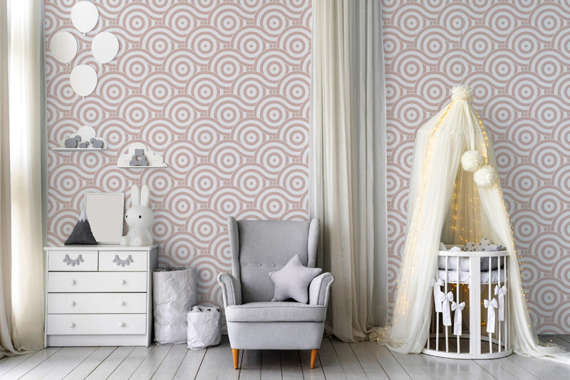 Children's room with pink wallpaper, crib, and gray armchair.