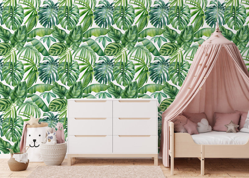 Children's room with tropical leaf wallpaper, white dresser, and pink canopy bed.