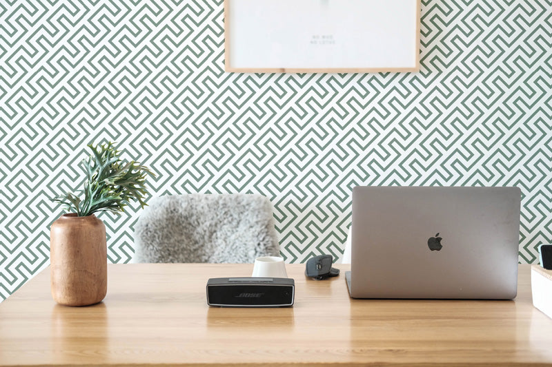 Laptop on a desk with decorative wallpaper.