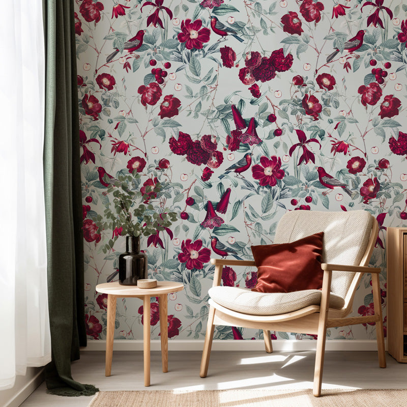 Floral wallpaper with red and green flowers in a room with a chair and side table.