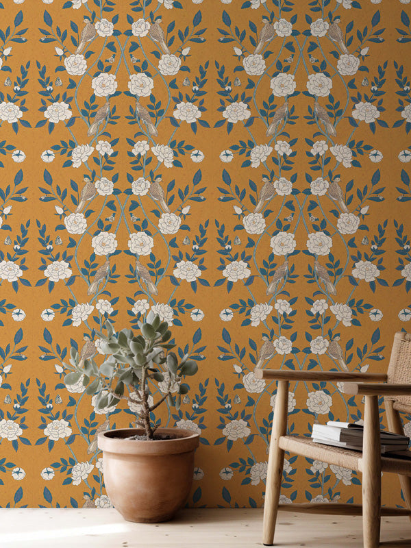 Room interior with a plant and wooden chair against a floral willian morris walpaper wall.