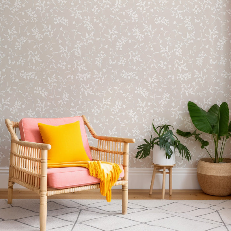 Wicker chair with pink cushion and yellow blanket against a floral wallpaper wall.