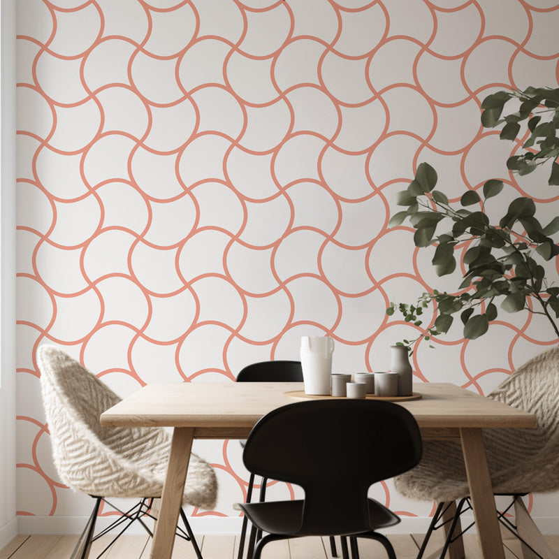 Dining area with a table and chairs against a wall with geometric pink wallpaper.